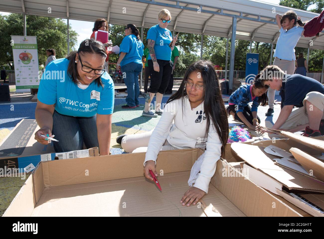 Austin Texas USA, aprile 20 2016: Un volontario adulto consiglia agli studenti della Cedars International Academy, che partecipano al programma Earth Day Cardboard Challenge della Cedars International Academy, mentre progettano e costruiscono una mostra scientifica in cartone e altri semplici prodotti riciclati. L'evento si è tenuto il giorno della Terra. ©Bob Daemmrich Foto Stock