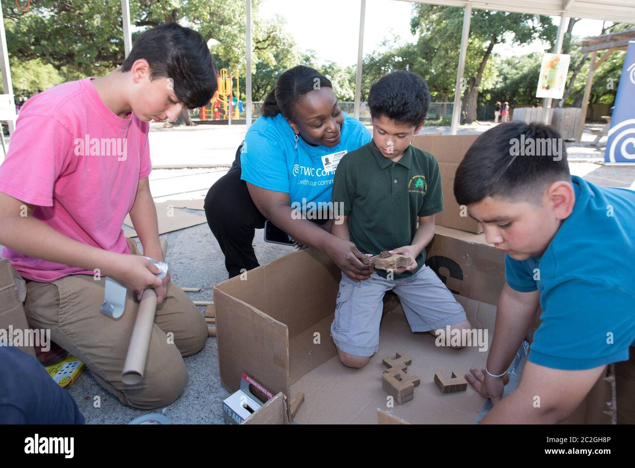 Austin Texas USA, aprile 20 2016: Un volontario adulto consiglia agli studenti della Cedars International Academy, che partecipano al programma Earth Day Cardboard Challenge della Cedars International Academy, mentre progettano e costruiscono una mostra scientifica in cartone e altri semplici prodotti riciclati. L'evento si è tenuto il giorno della Terra. ©Bob Daemmrich Foto Stock