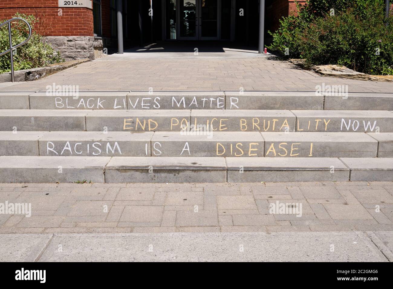 Black Lives Matter messaggio con fine polizia brutalità e razzismo è malattia scritta in Chalk sui passi scolastici in Glebe-Ottawa, Canada Foto Stock