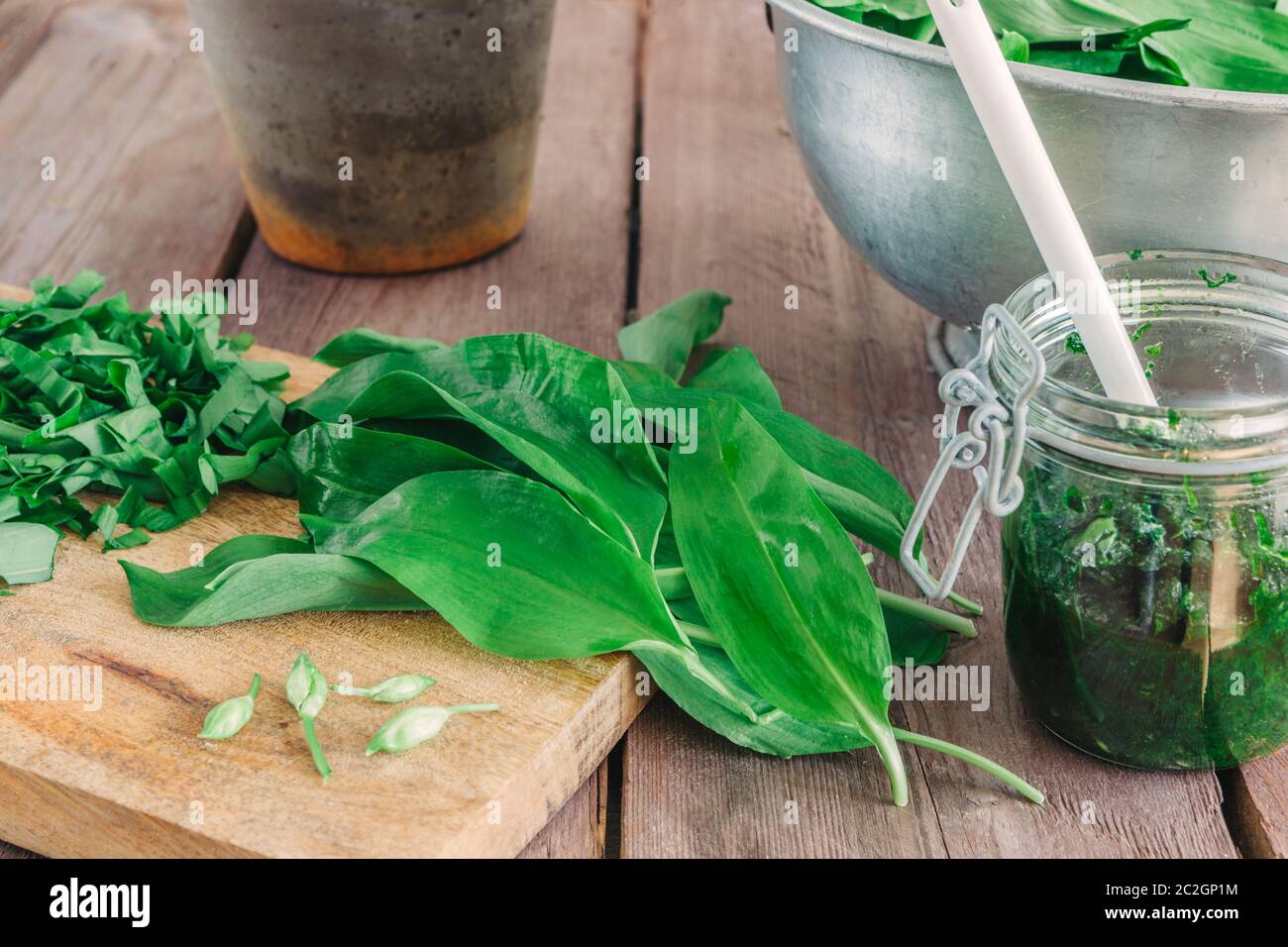 Ramson verde fresco con un bicchiere di pesto e una ciotola su sfondo di legno. Foto Stock