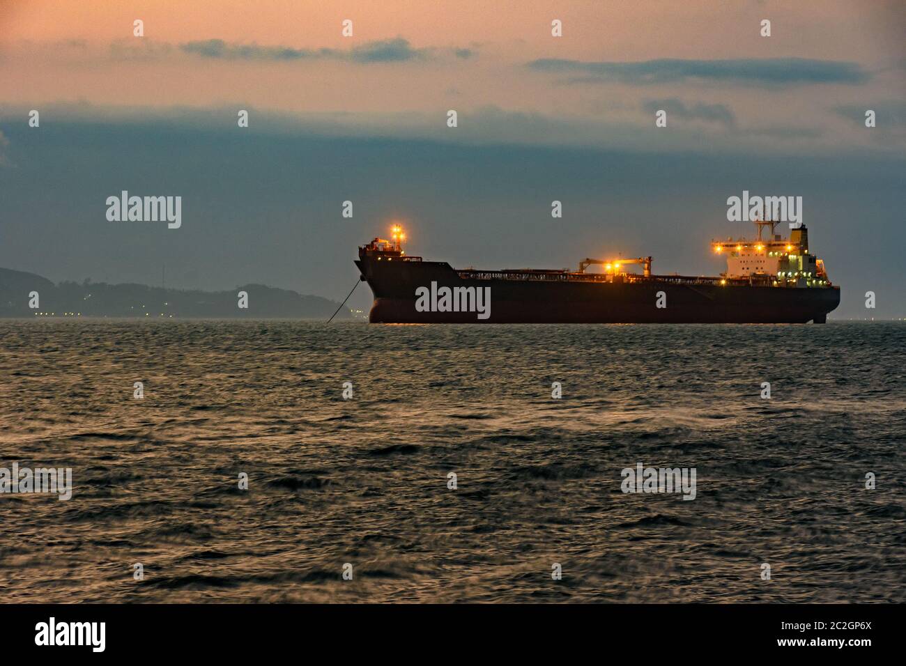 Grande nave da carico ancorata nelle acque dell'isola di Ilhabela al tramonto Foto Stock