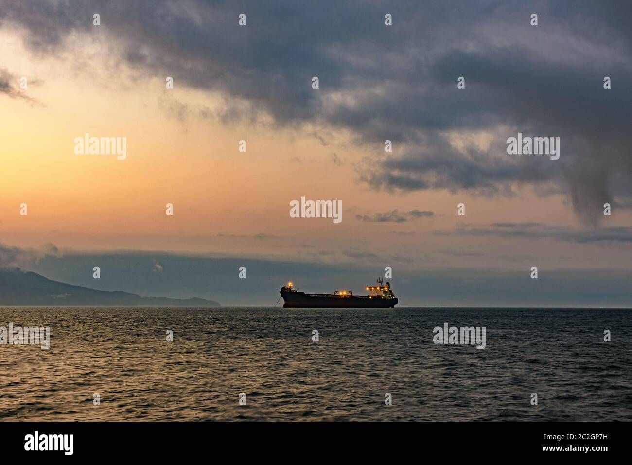 Nave da carico ancorata nelle acque dell'isola di Ilhabela al tramonto Foto Stock