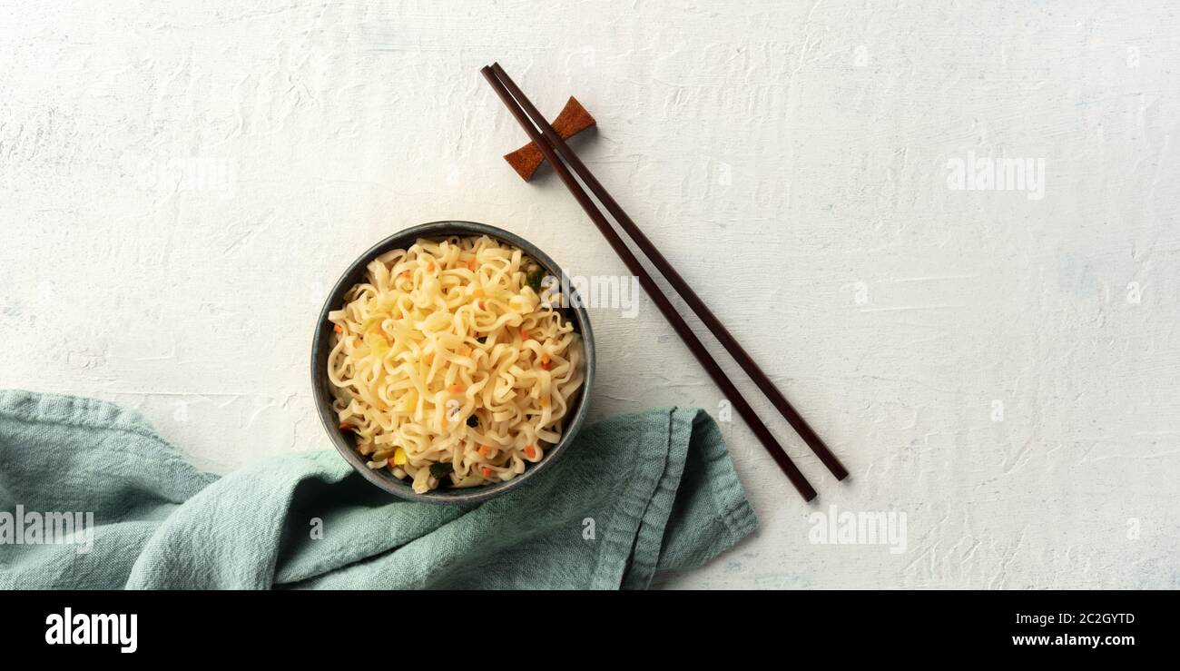Un panorama di spaghetti soba istantanei con carote, sparati dalla cima con bastoncini e spazio per la copia. Una metafora per una cena per on Foto Stock