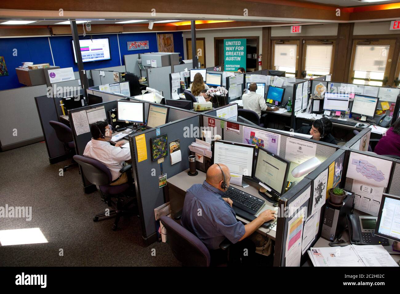 Austin Texas USA, marzo 28 2014: I rappresentanti del servizio clienti lavorano in cubicoli presso il call center della United Way of Greater Austin, aperto 24 ore su 24, dove i residenti del Texas centrale possono ottenere risposte alle domande sull'iscrizione all'assicurazione sanitaria, alla preparazione alle catastrofi e ai servizi sociali. ©Bob Daemmrich Foto Stock