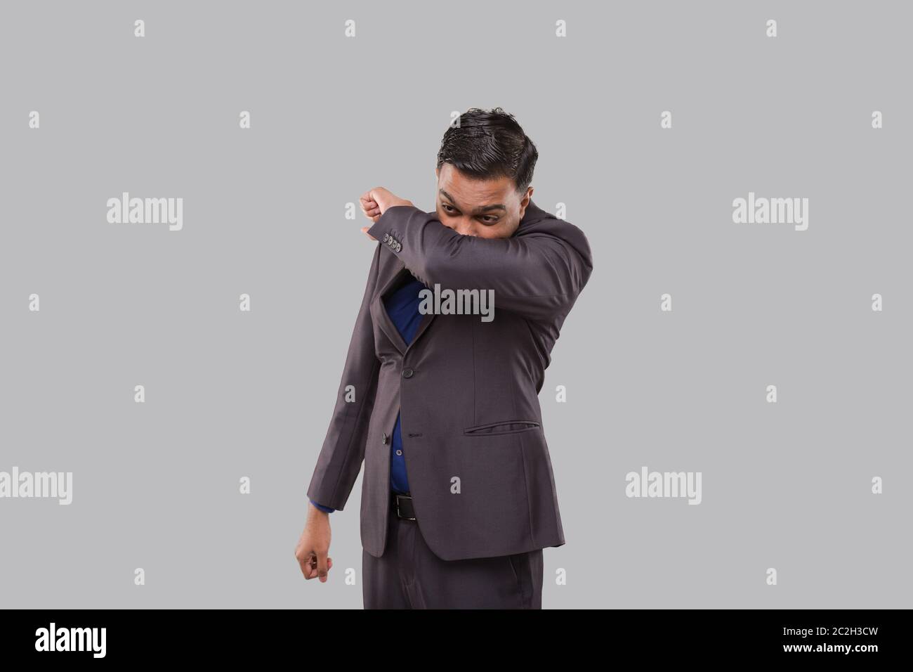 Uomo d'affari starnutendo Virus stile. Indiano Business Man starnutire a gomito. Foto Stock