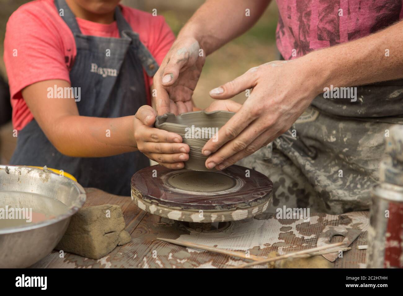 Primo piano di una mano di Potter scolpisce un caraffa di creta su una ruota di Potter Foto Stock