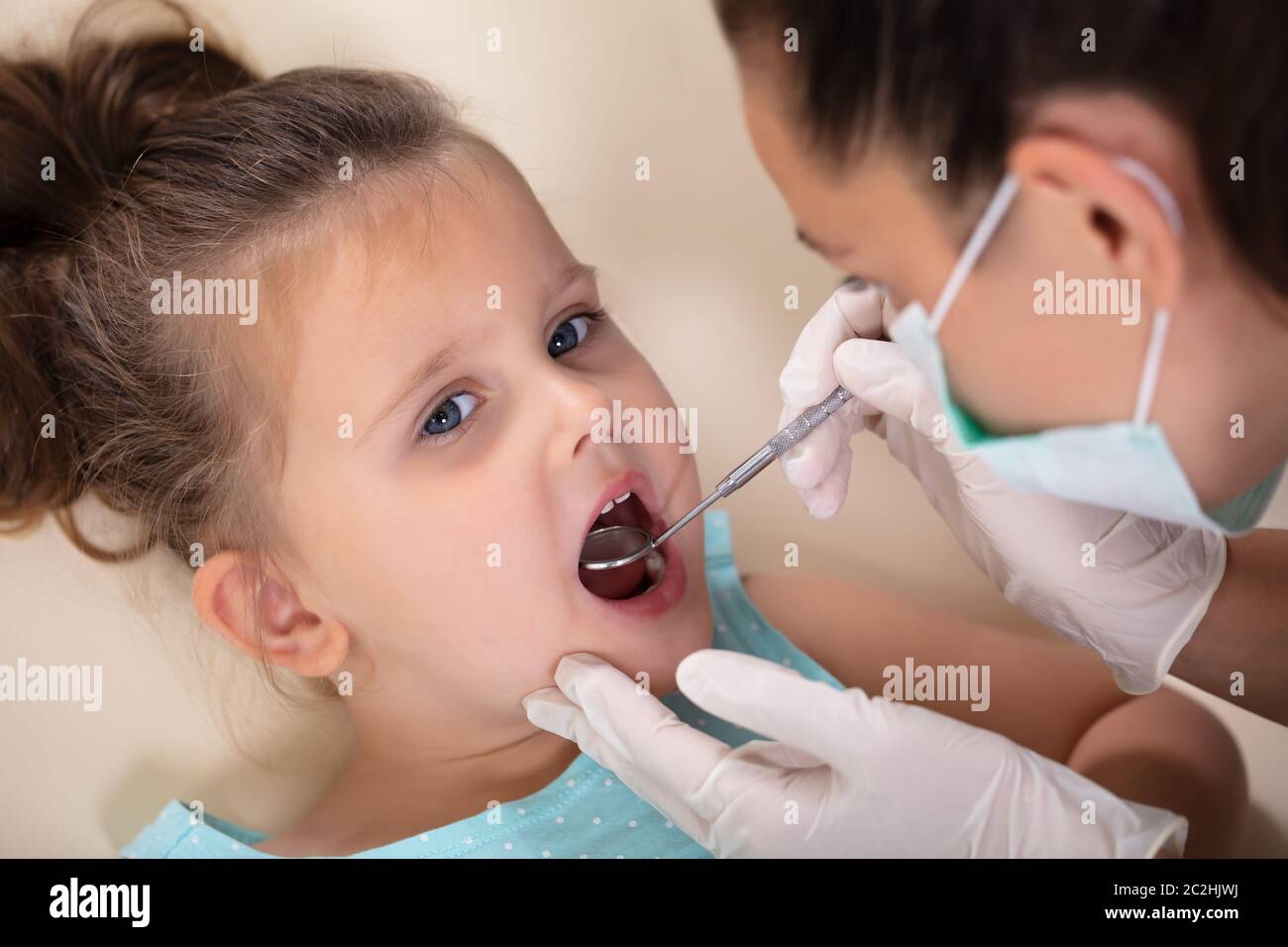 Close-up di una femmina di dentista con specchio esamina i denti di poco in ansia ragazza Foto Stock