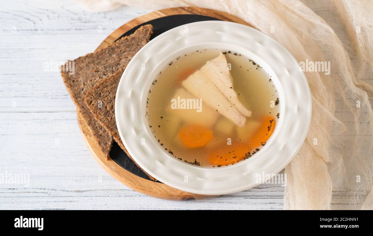 Zuppa di pesce in ciotola bianca con pane integrale su tavola bianca. Patate, carote, zuppa di pesce di trota di fiume. Pronto a mangiare Foto Stock