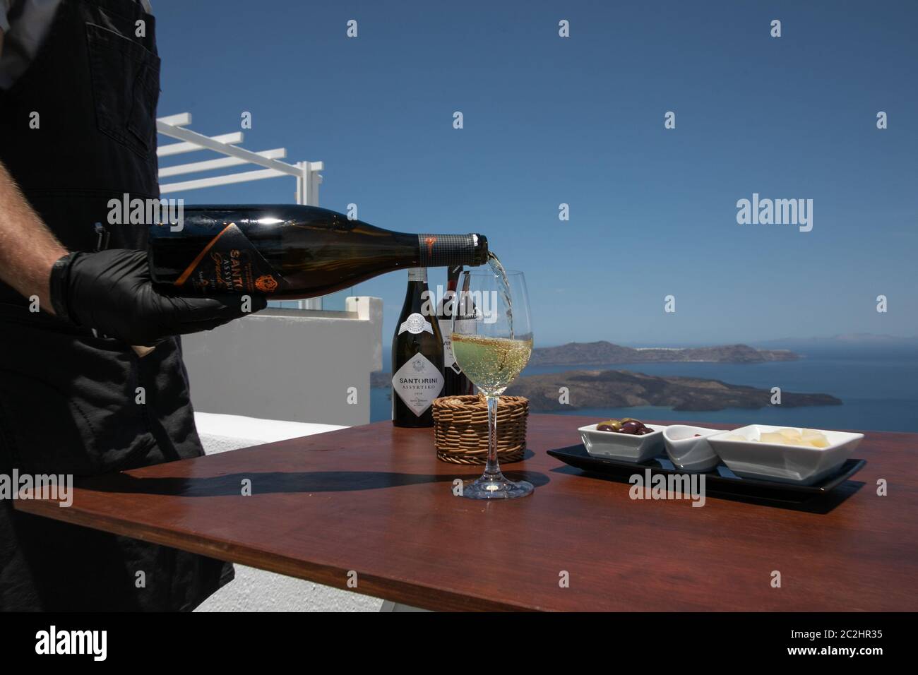 Santorini, Grecia. 17 Giugno 2020. Un cameriere versa un bicchiere di vino Assyrtiko sull'isola di Santorini, Grecia, 14 giugno 2020. Nonostante le sue piccole dimensioni, l'isola di Santorini vanta tre prodotti certificati dall'Unione europea (UE) Denominazione di origine protetta (DOP): Pomodori ciliegini, fava e vino. PER ANDARE CON "caratteristica: Santorini Grecia cerca equilibrio tra turismo, agricoltura" credito: Lefteris Partsalis/Xinhua/Alamy Live News Foto Stock