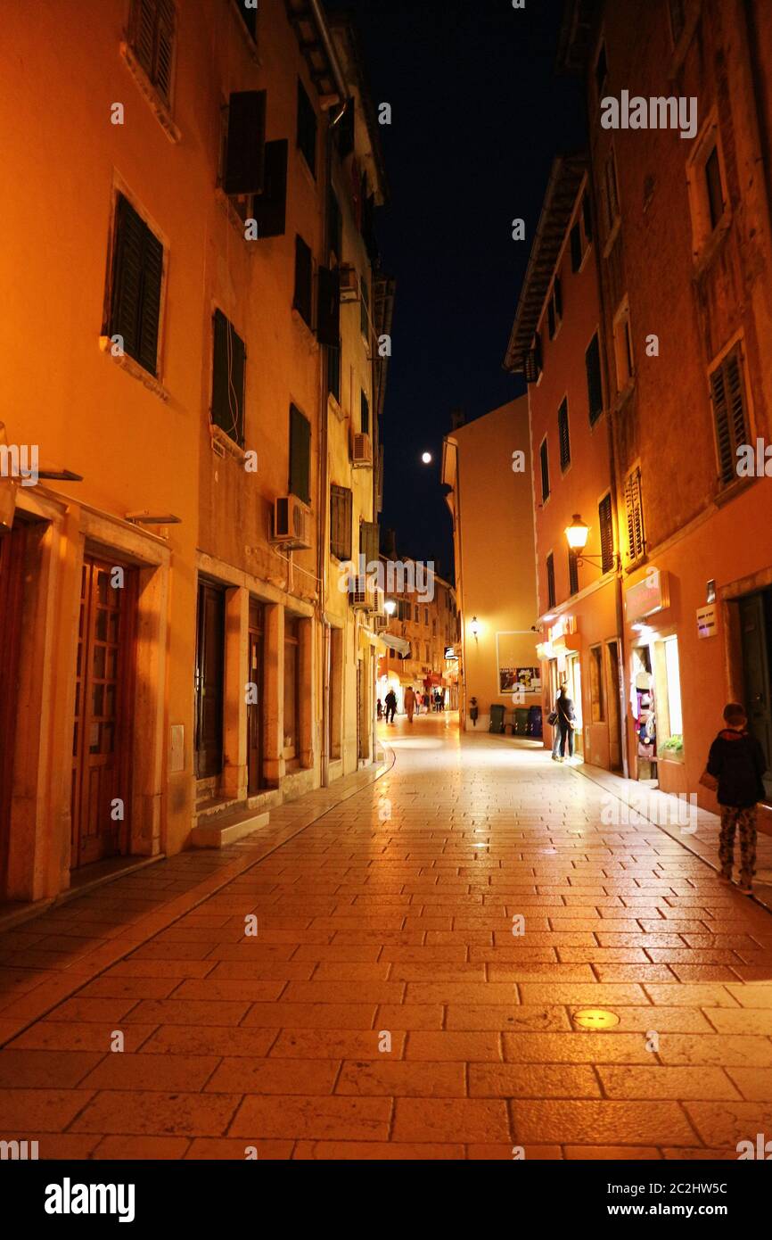 Un vicolo con luci arancioni di notte a Rovigno, Croazia. Foto Stock