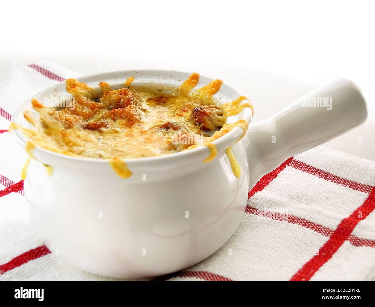 Zuppa di cipolla in un recipiente bianco. Un piatto classico della cucina francese che consiste principalmente di cipolle cotte lentamente in brodo di manzo e formaggio alla griglia sulla parte superiore. Foto Stock