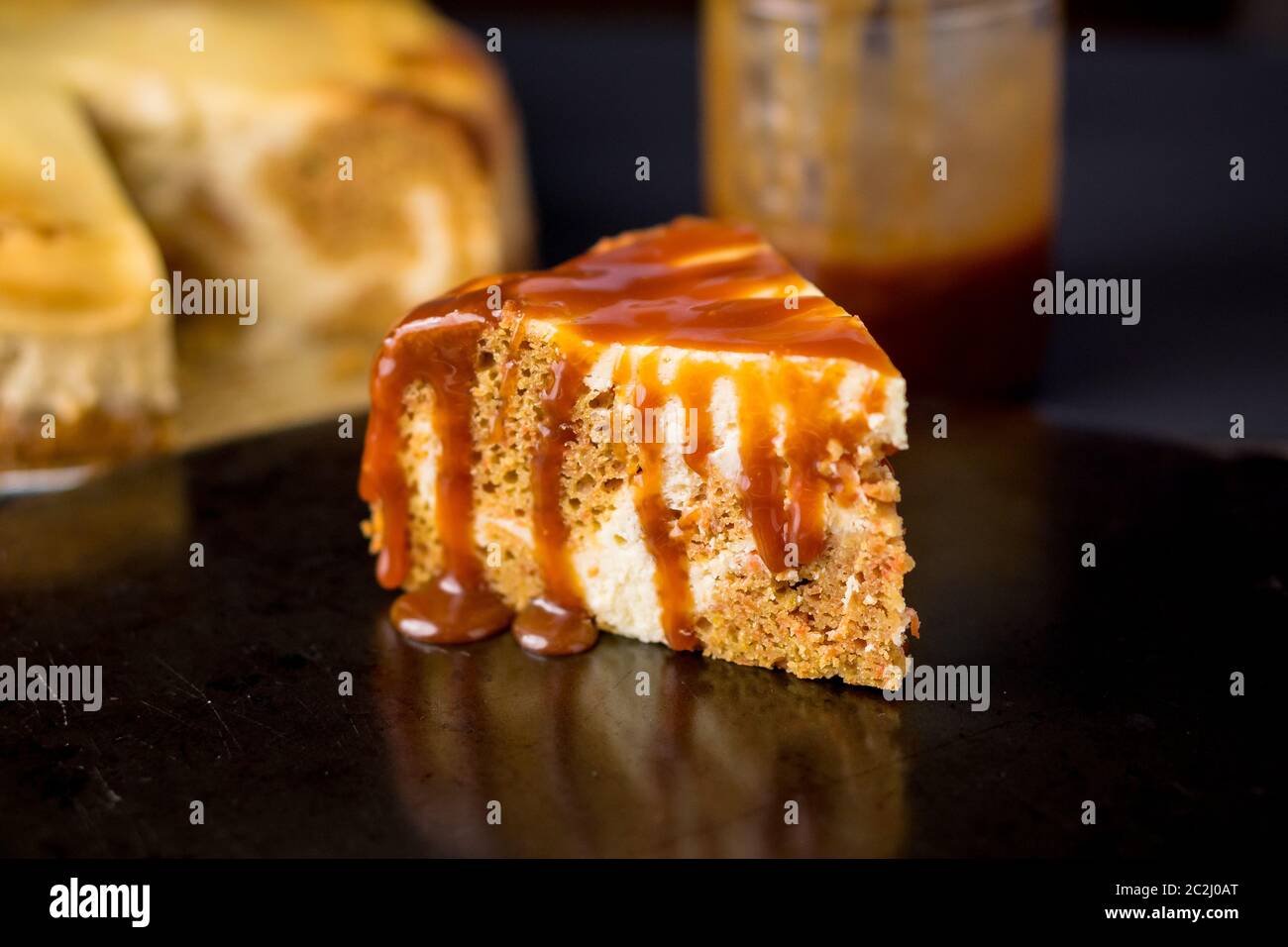 Fetta di torta di marmo che è un mix di torta di carote e cheesecake roteati insieme e conditi con salsa al caramello. Un delizioso dolce cremoso. Foto Stock