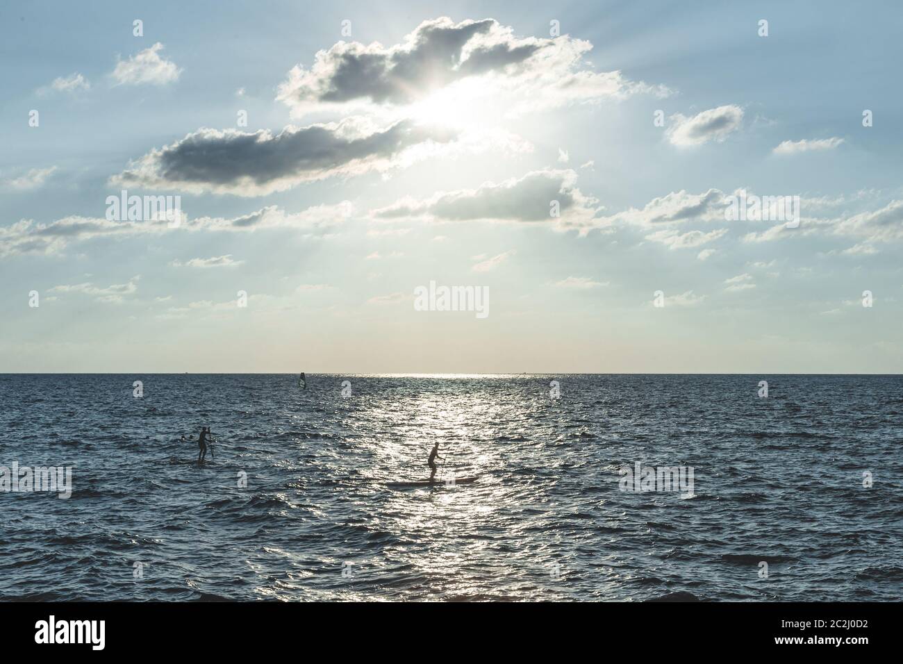 Uomo paddleboard nel Mar Mediterraneo vicino alla spiaggia di Tel Aviv. A differenza del surf tradizionale, i paddle boarders in piedi utilizzano una pagaia per spingere il themselve Foto Stock