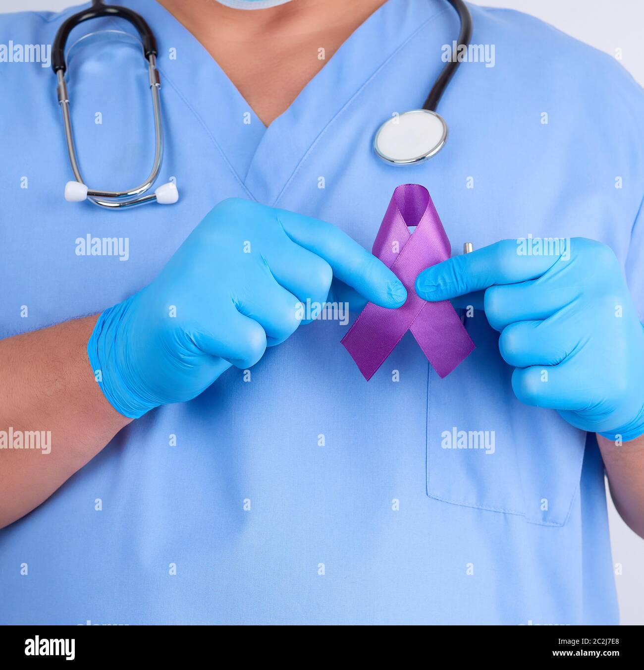 Dottore in uniforme blu e guanti in lattice contiene un nastro viola come un simbolo di inizio di ricerca e di controllo della malattia, il morbo di Alzheimer, fibrosi cistica, Foto Stock