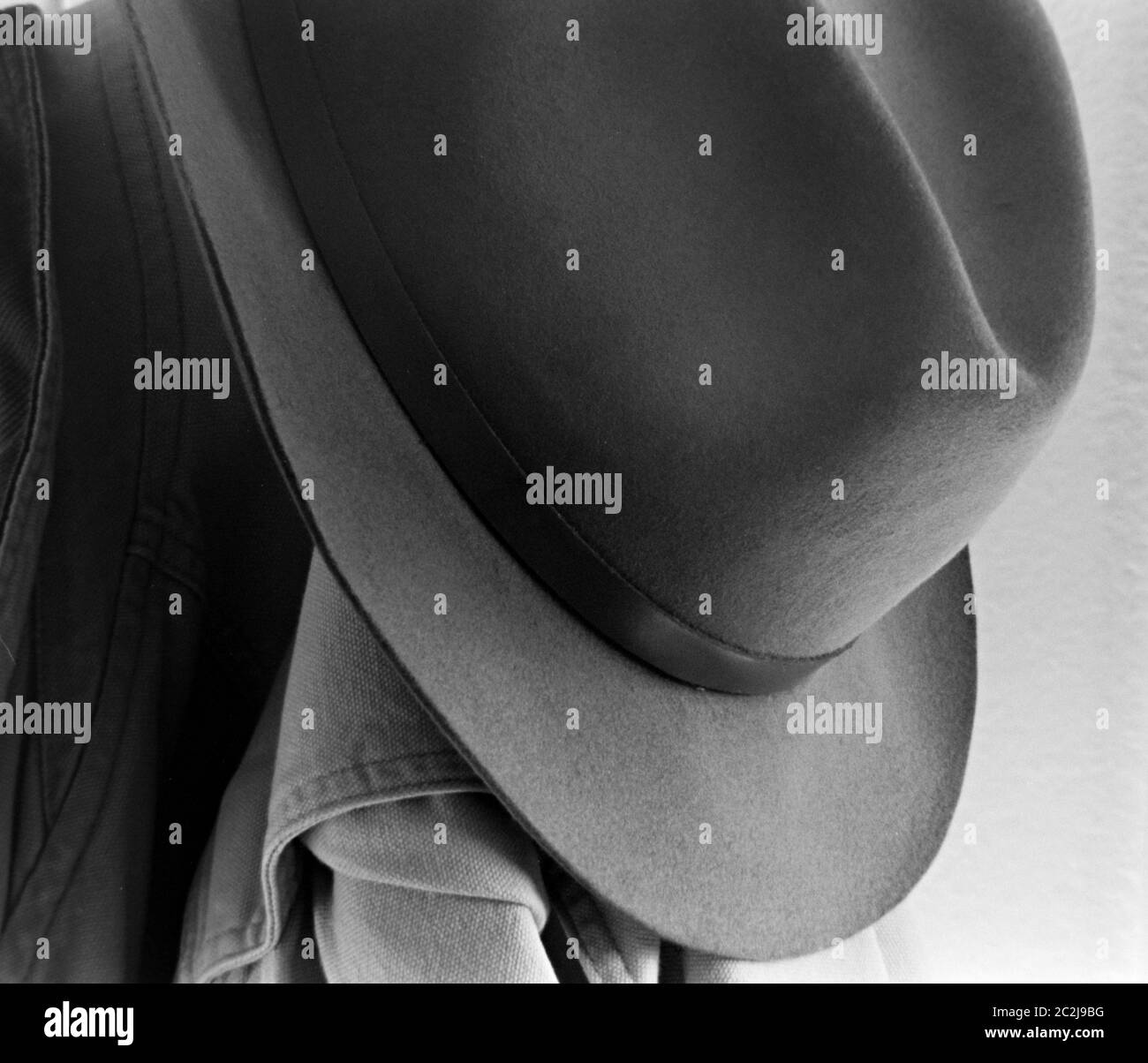 Fedora Hat Hung 1950 su un gancio a cappotto con una giacca da campo in tela, fotografia in bianco e nero, primo piano Foto Stock