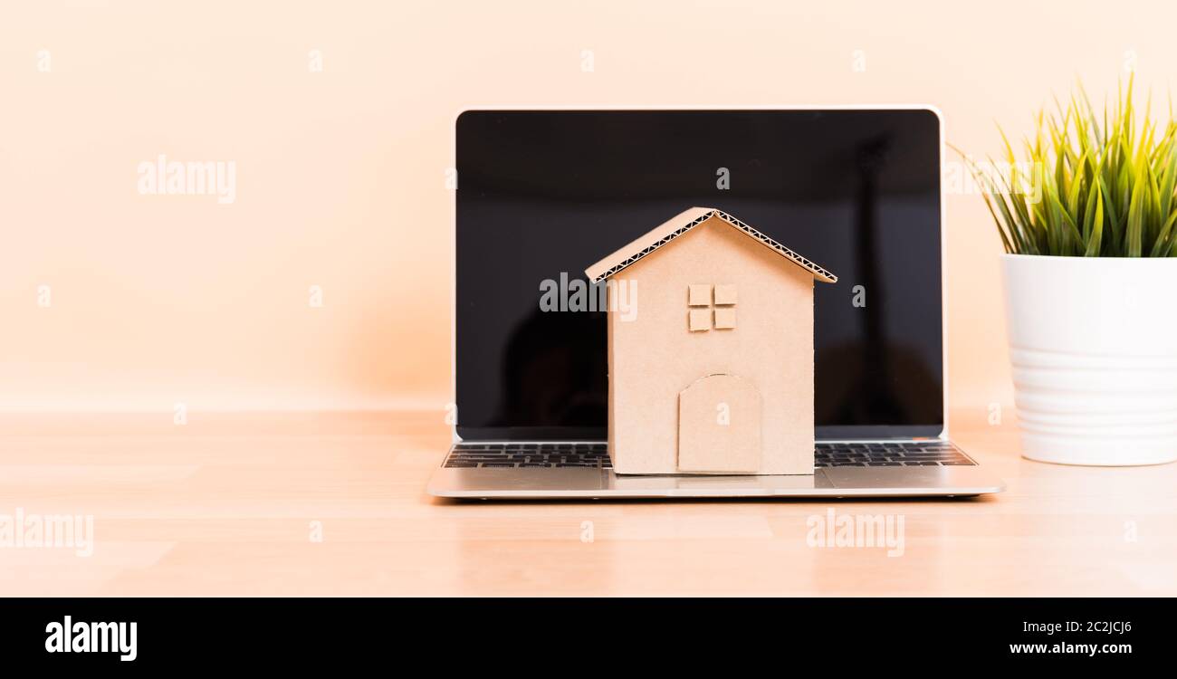 Carta cartone modello di casa e computer laptop, ipoteca sui beni immobili affittare acquistare concept Foto Stock