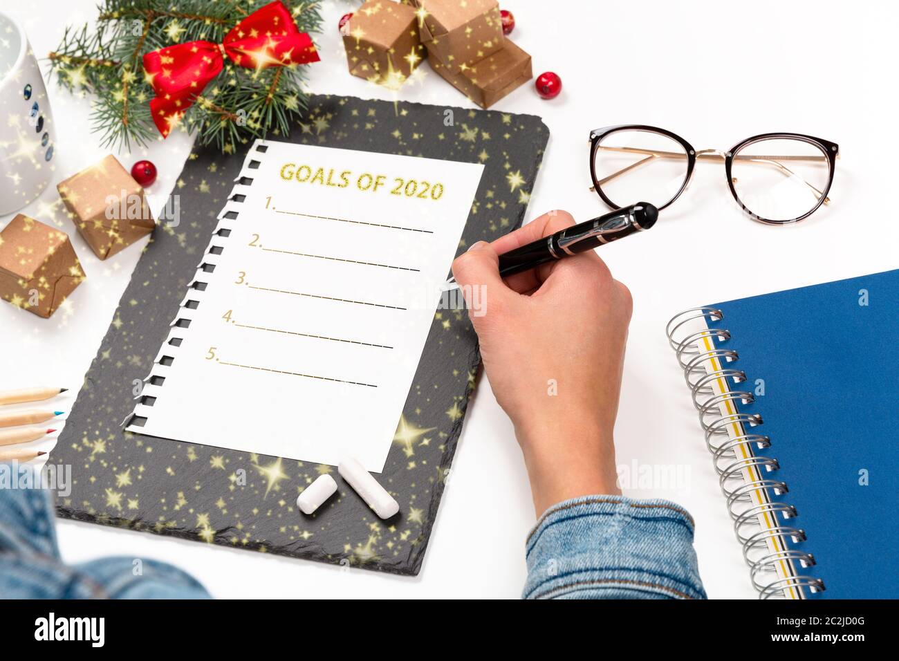 La donna è la scrittura a mano 2020 Obiettivi in notebook decorato con decorazioni di Natale. Anno nuovo concetto di risoluzione Foto Stock