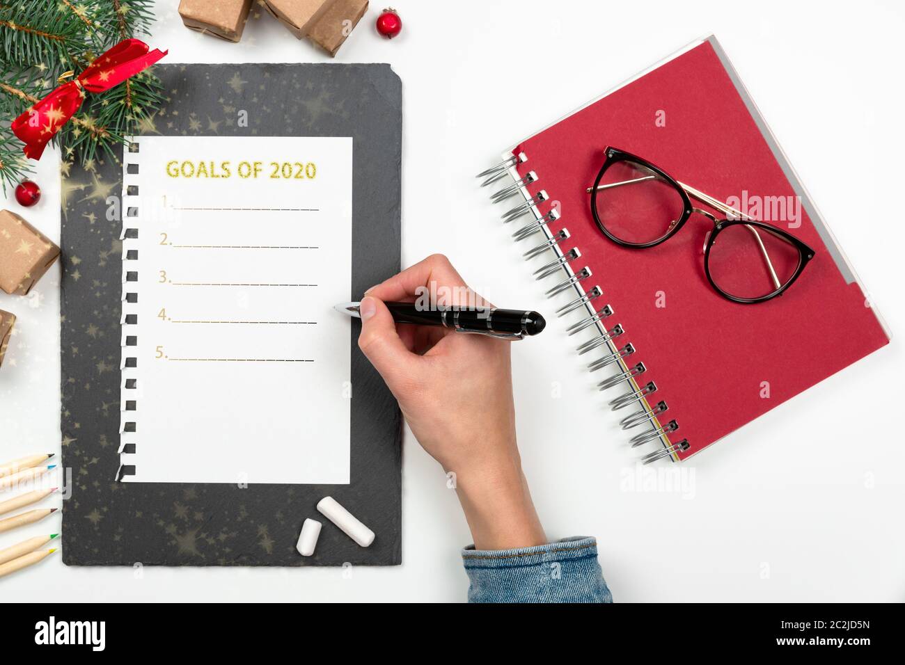 La donna è la scrittura a mano 2020 Obiettivi in notebook decorato con decorazioni di Natale. Anno nuovo concetto di risoluzione Foto Stock