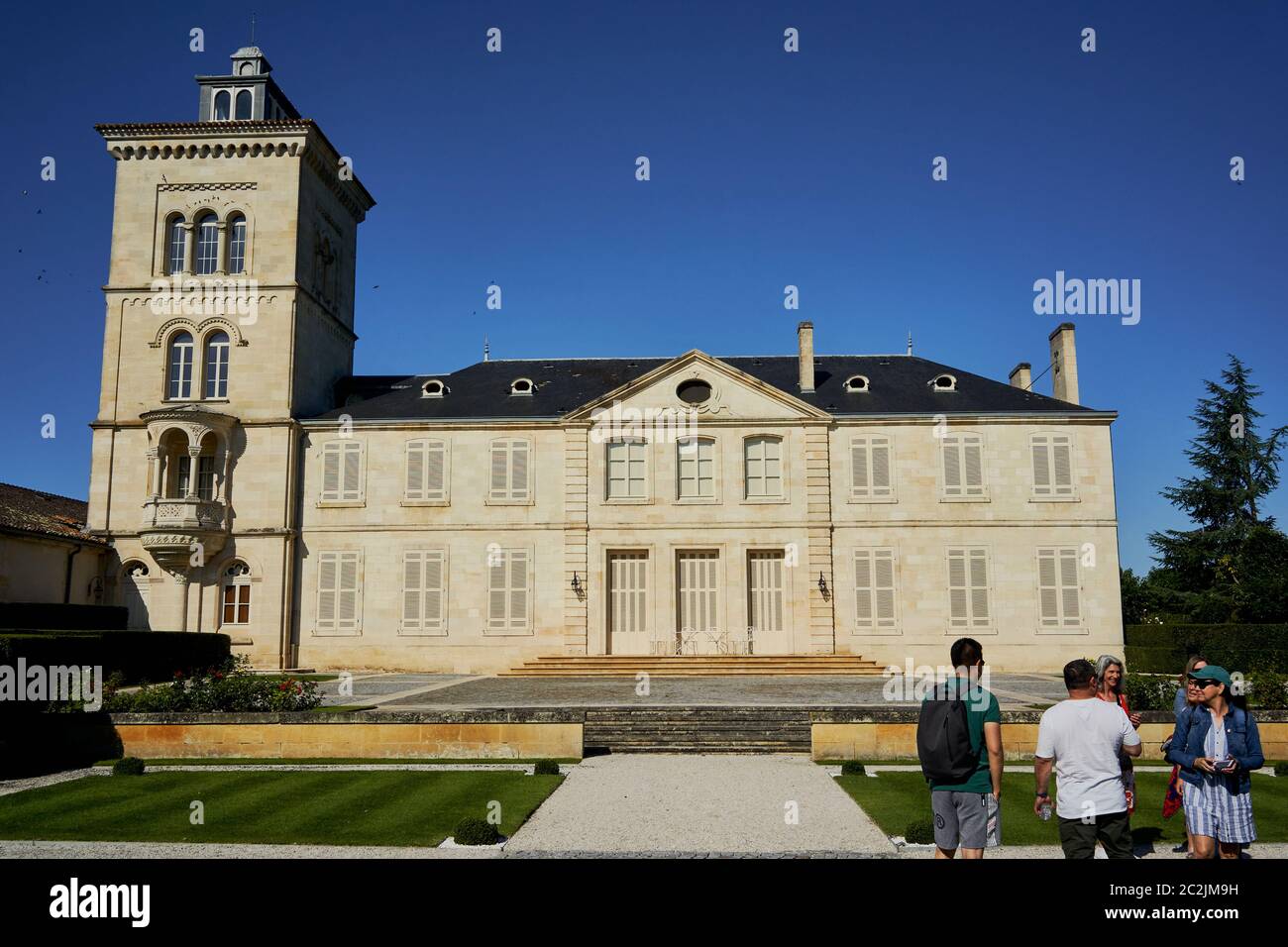 L'edificio principale color crema dello Chateau Lagrange con la sua alta torre sinistra, visitatori sul vialetto di ghiaia, Saint-Julien, Bordeaux, Francia Foto Stock