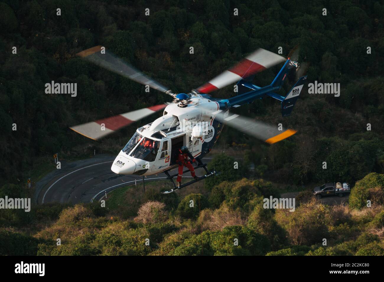 Un membro dell'equipaggio di un elicottero di soccorso supervisiona l'abbassamento delle attrezzature sul sito di un'auto che cadde su una ripida riva a Christchurch, Nuova Zelanda Foto Stock