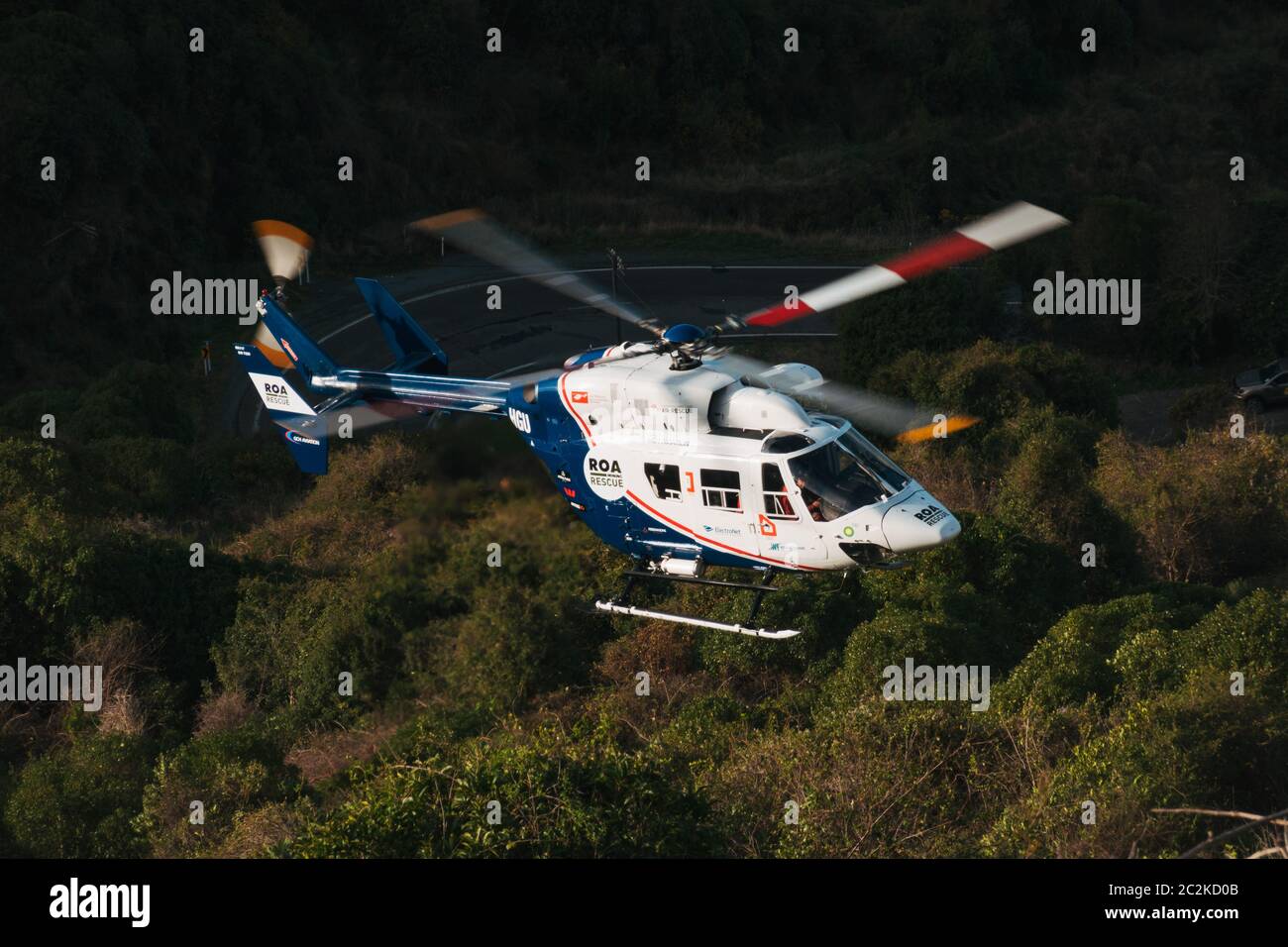 Un elicottero di salvataggio Airbus H145 abbassa l'attrezzatura al sito di un'auto che è caduto giù una banca ripida su Dyers Pass Road, Christchurch, Nuova Zelanda Foto Stock