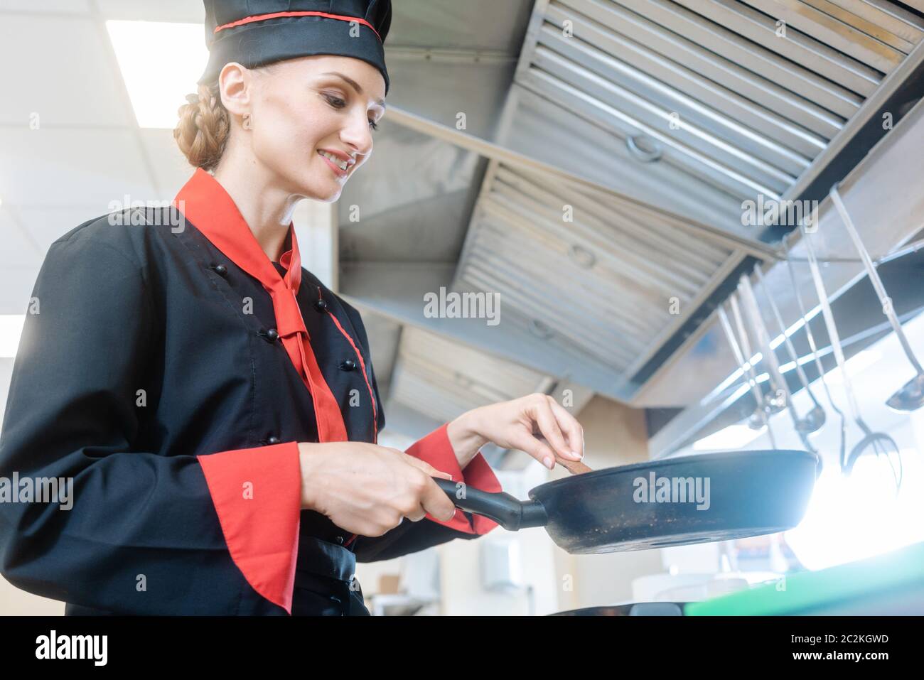 Una chef femminile che mescola il pasto in una padella Foto Stock