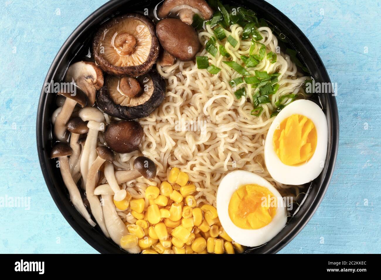 Ramen close-up. Soba con uova, funghi e ortaggi, ripresa dall'alto su uno sfondo blu Foto Stock