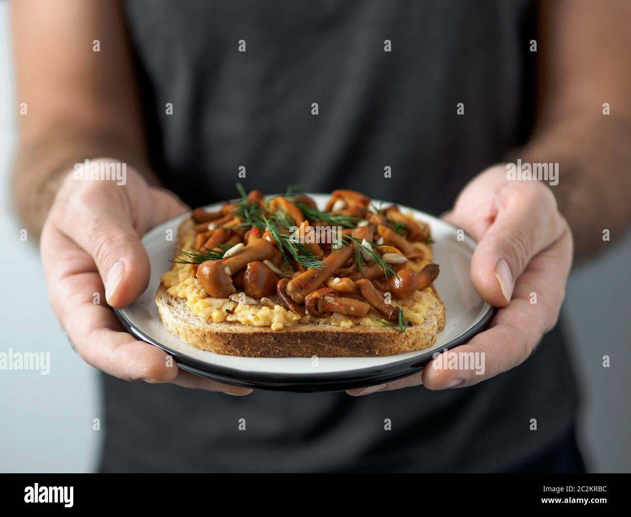 Panino vegano con funghi in mani maschili Foto Stock