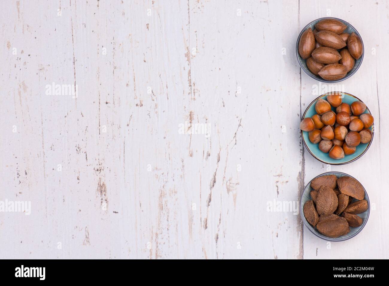 Mix di nocciole su sfondo bianco testurizzato in legno, spazio vuoto per la copia Foto Stock