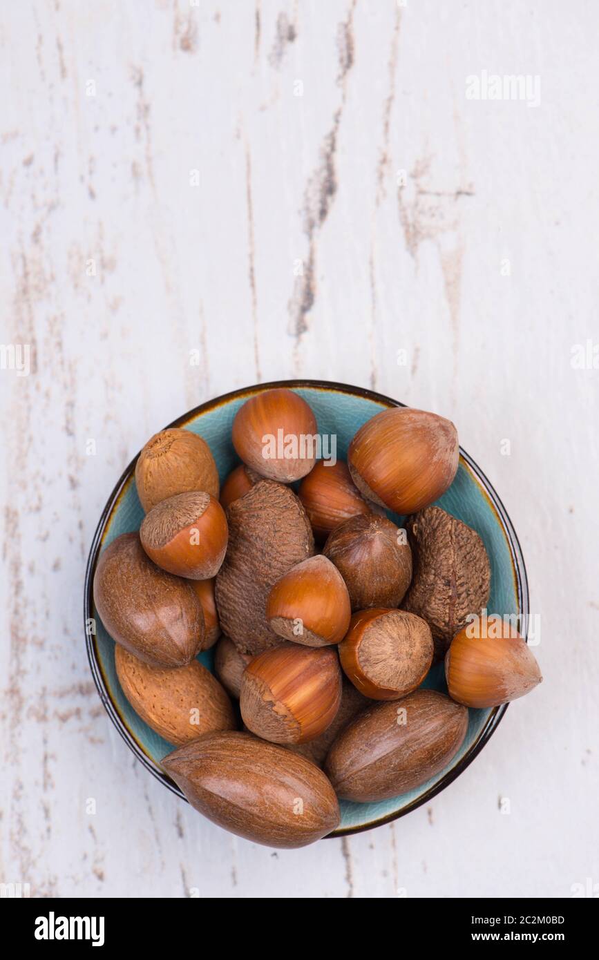 Mix di nocciole su sfondo bianco testurizzato in legno, spazio vuoto per la copia Foto Stock