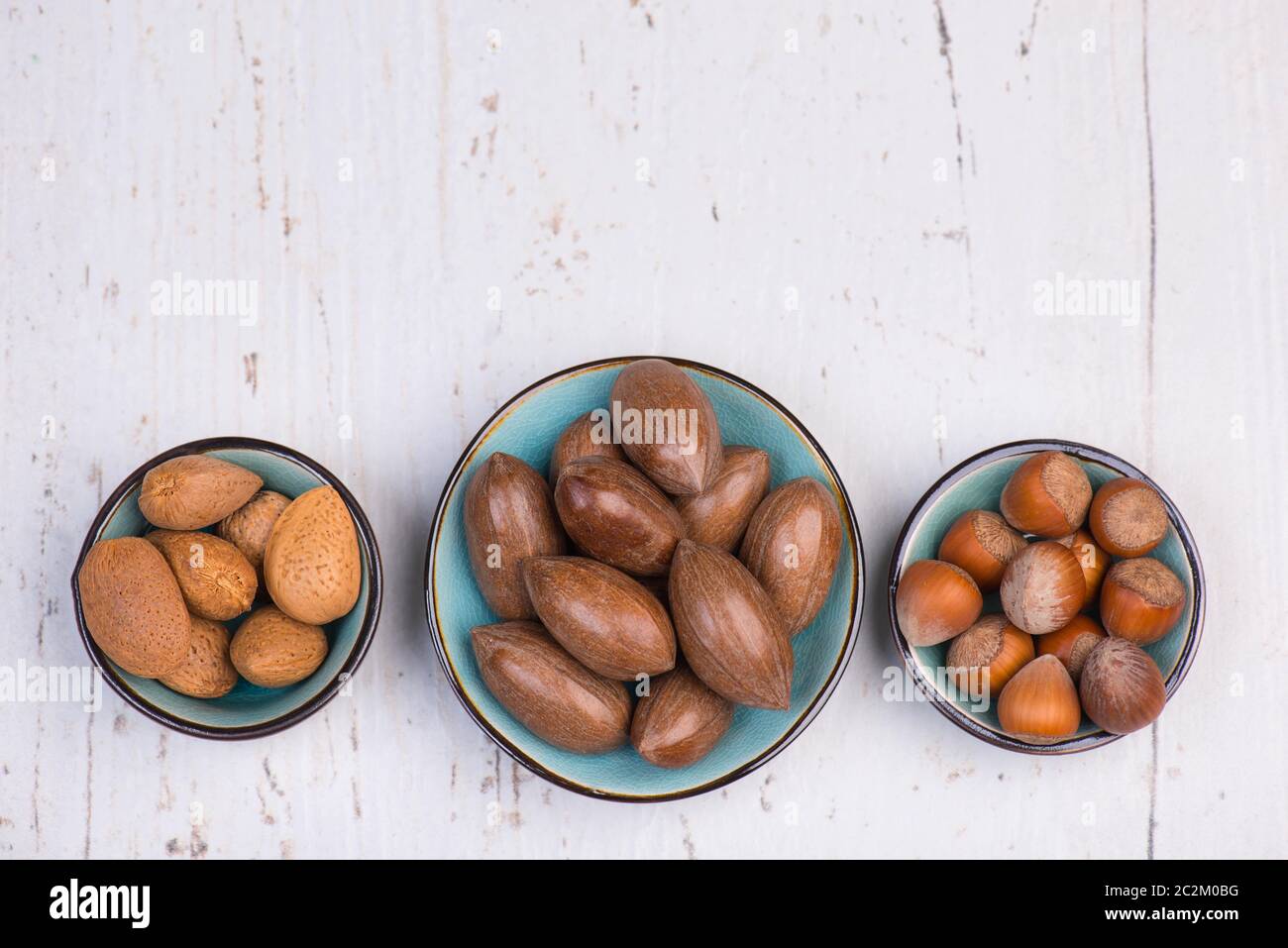 Mix di nocciole su sfondo bianco testurizzato in legno, spazio vuoto per la copia Foto Stock