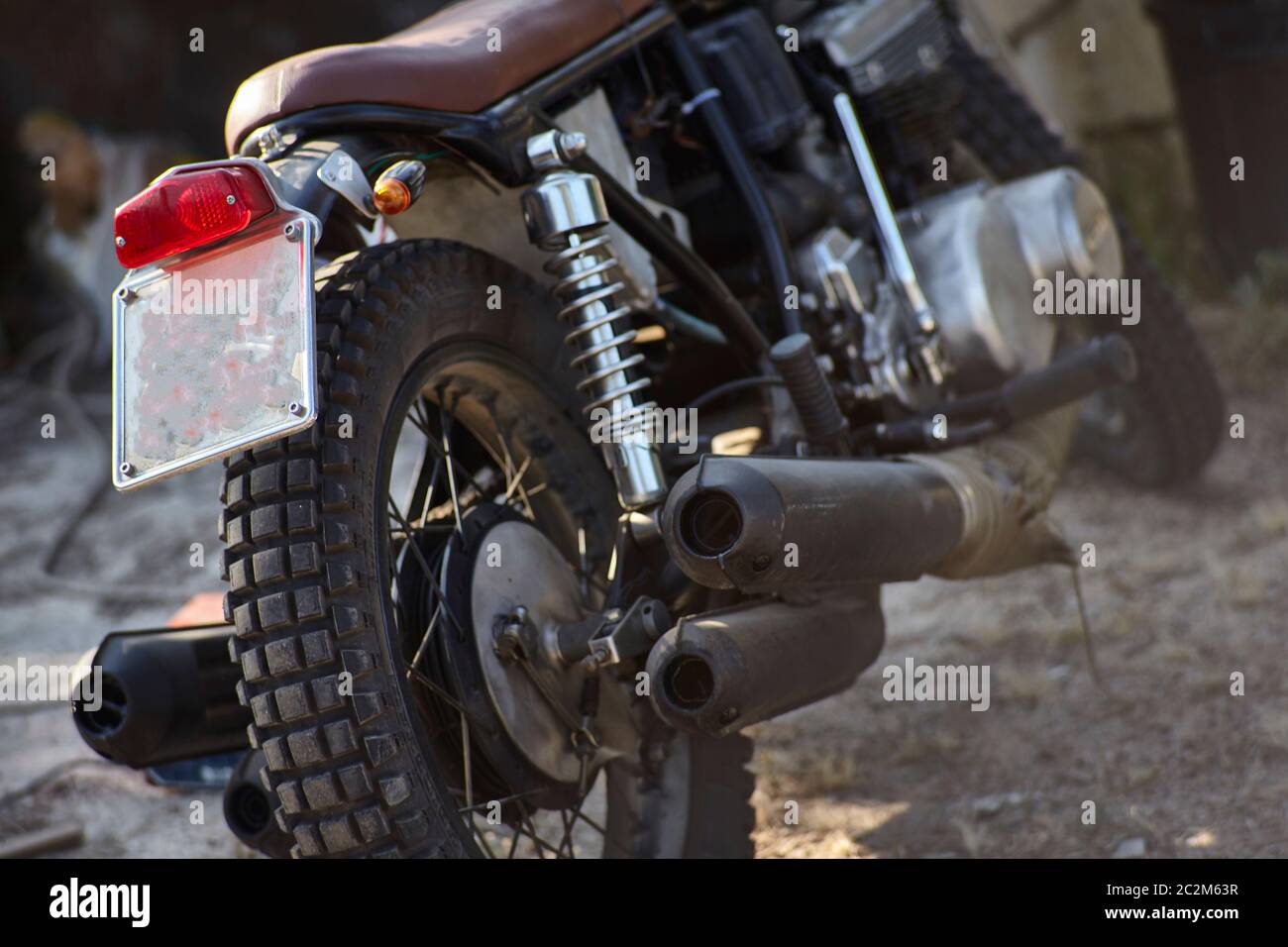 Vita still di una parte posteriore di una motocicletta d'epoca con tubi di scarico ben visibili, la ruota e le numerose parti meccaniche di cui è fatta. Foto Stock