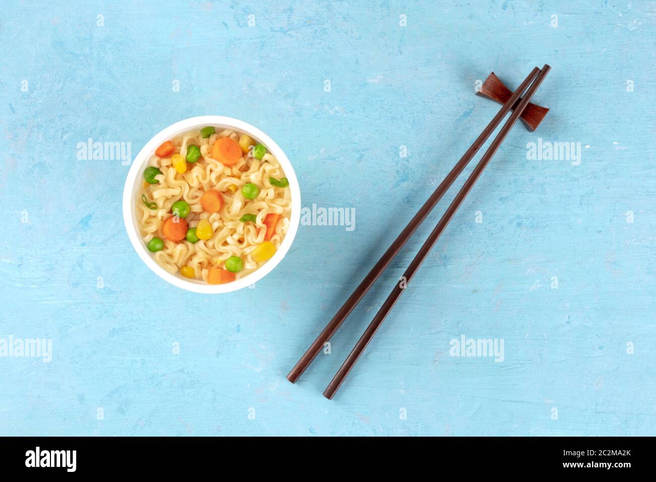 Ramen cup, tagliatelle istante in una tazza di plastica, overhead shot con bacchette e un posto per il testo su sfondo blu Foto Stock