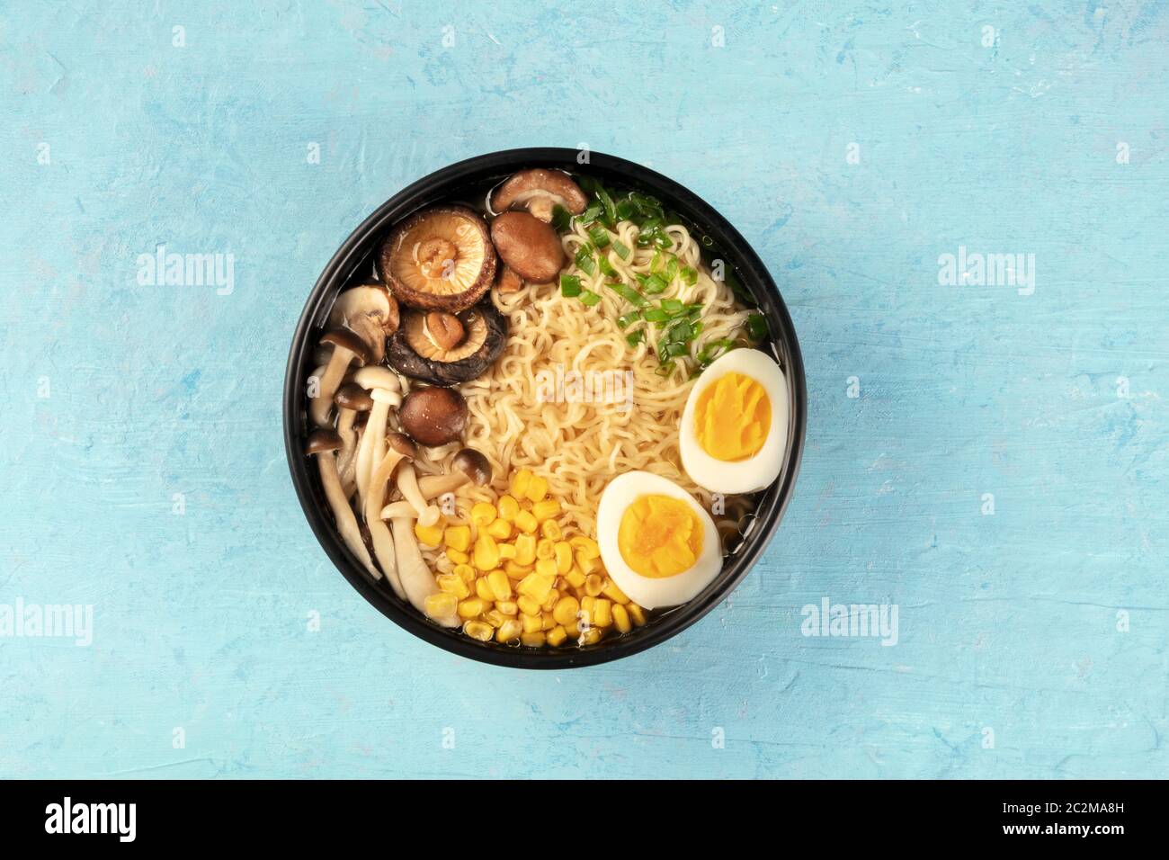 Ramen. Soba Noodles con uova, funghi e ortaggi, overhead shot su uno sfondo blu Foto Stock