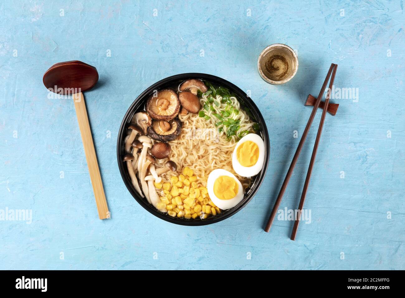 Zuppa di ramen. Tagliatelle di Soba con uova, funghi shiitake e verdure, sparate dall'alto con sake, cucchiaio di legno tradizionale, un Foto Stock