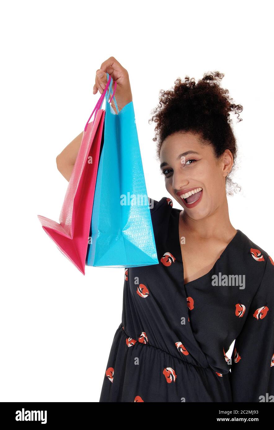 Una bella donna sorridente multirazziale in piedi con la sua borsa da shopping in primo piano, isolato per sfondo bianco Foto Stock