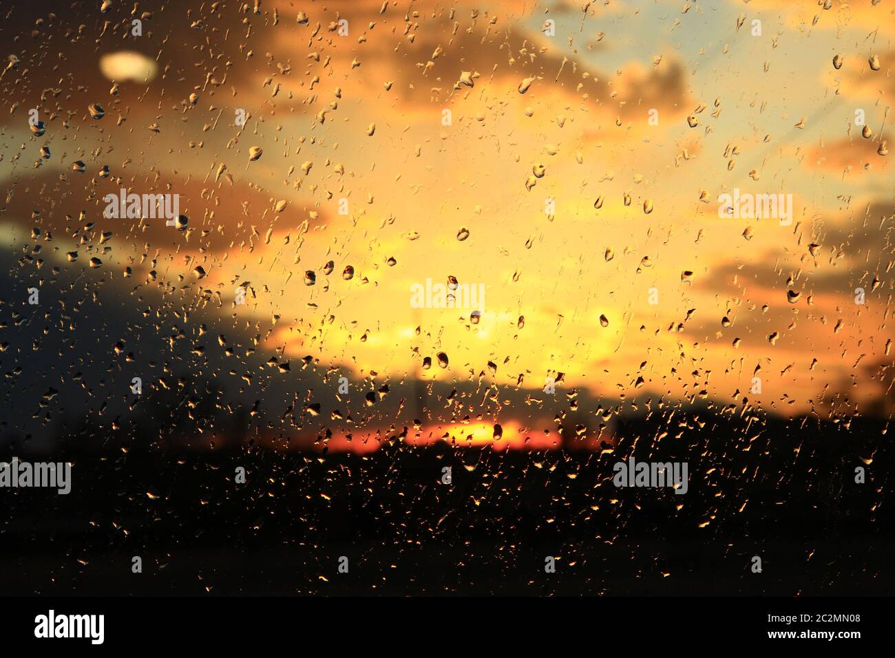 Pioggia fuori finestra sullo sfondo del tramonto. La pioggia cade sul vetro durante la pioggia Foto Stock