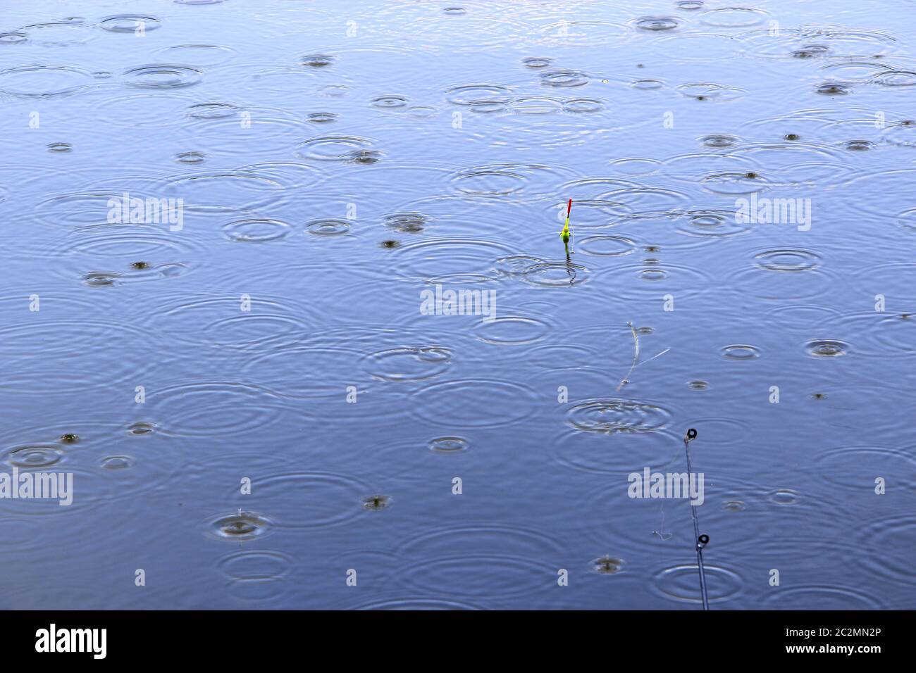Pioggia sul fiume durante la pesca. Pesca galleggia in acqua mentre piove. Gocce d'acqua cadono sulla superficie o Foto Stock