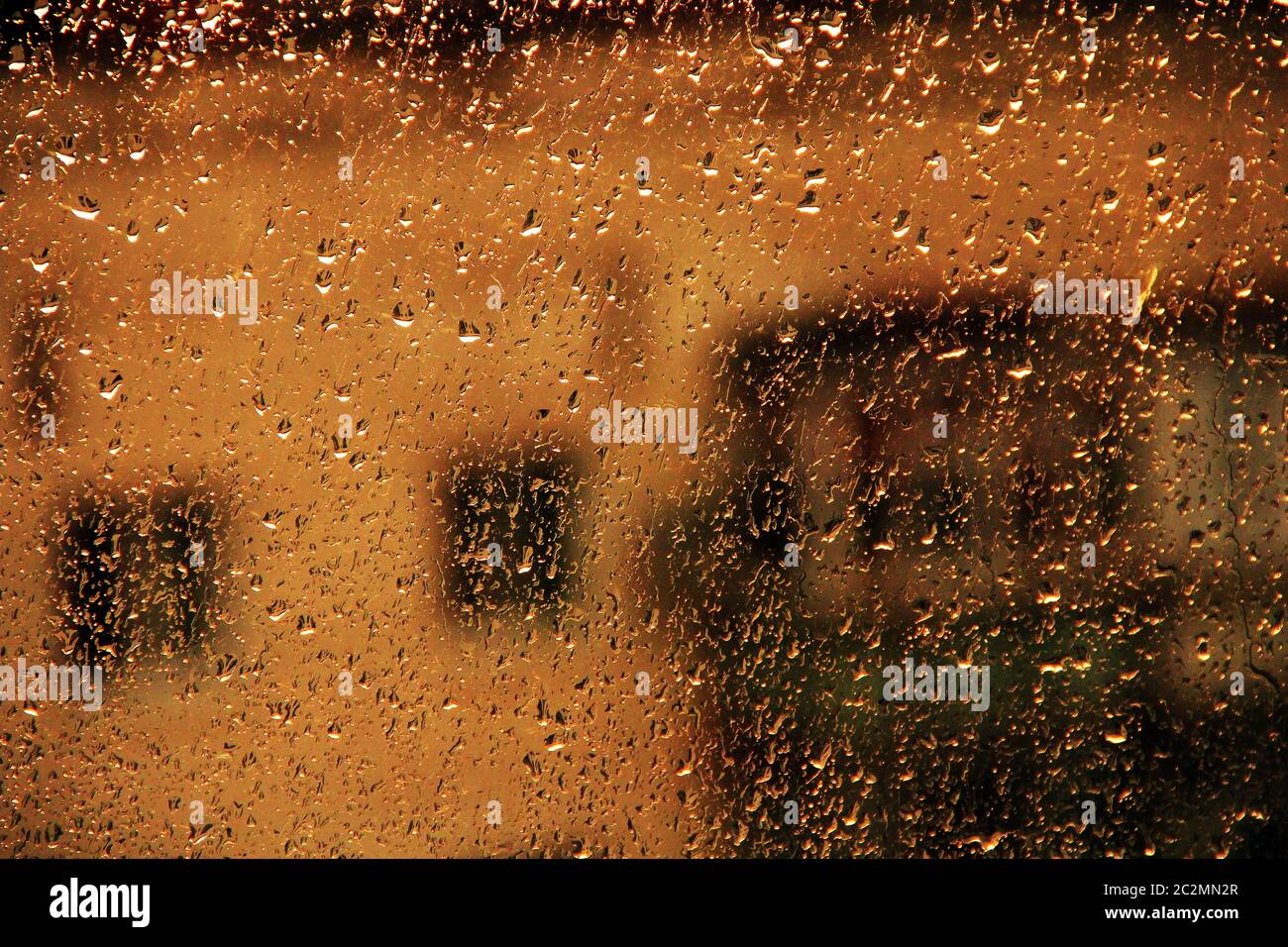 Pioggia fuori finestra sullo sfondo di casa a molti piani. Gocce d'acqua che cadono sul vetro durante la rai Foto Stock