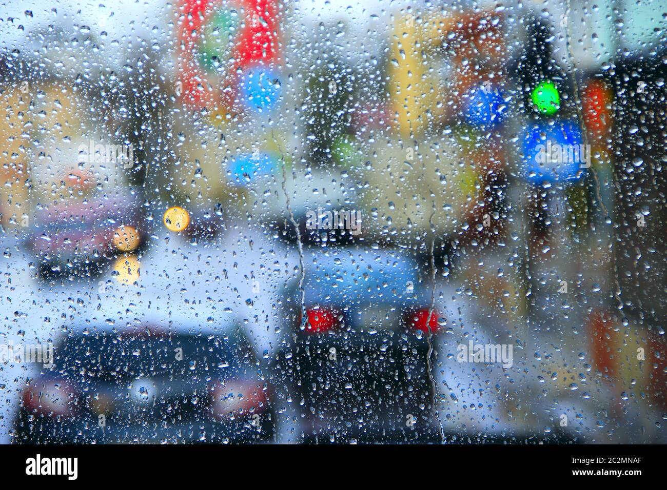 Pioggia fuori dalla finestra sullo sfondo delle luci della città. Gocce d'acqua che cadono sul vetro durante la pioggia Foto Stock