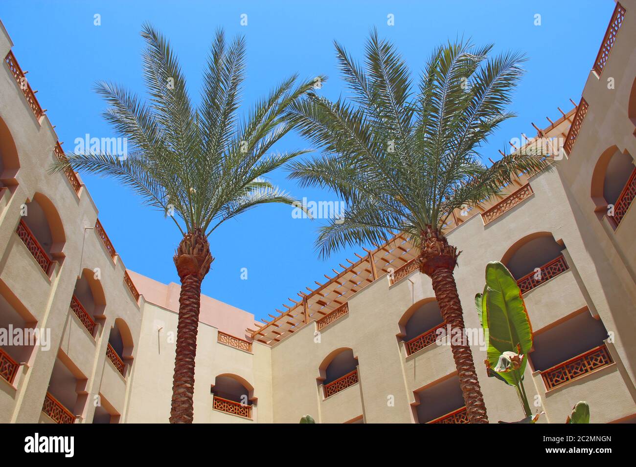 Vista dell'edificio del resort con palme. Resort egiziano. Vacanze tropicali Foto Stock