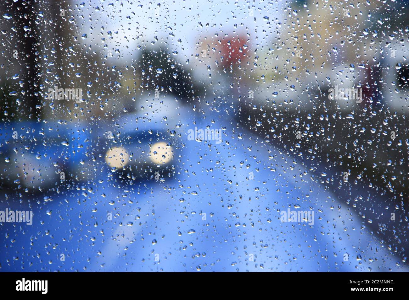 Pioggia sul vetro. Pioggia fuori dalla finestra sullo sfondo delle luci della città. Gocce d'acqua che cadono sul vetro Foto Stock