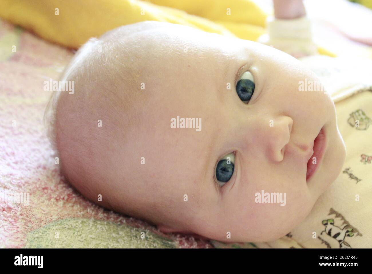 Ritratto di bambino sorridente con occhi blu. Neonato che guarda la madre Foto Stock