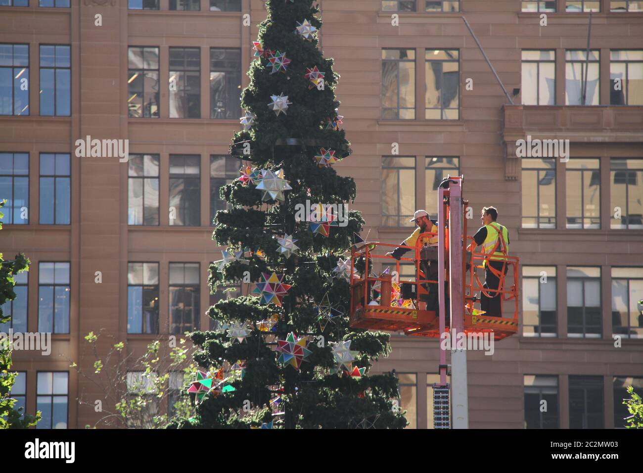 I lavoratori vengono sollevati in un ‘picker’ (gru a cesto) per fissare gli ornamenti all’albero di Natale di Martin Place, Sydney. Foto Stock