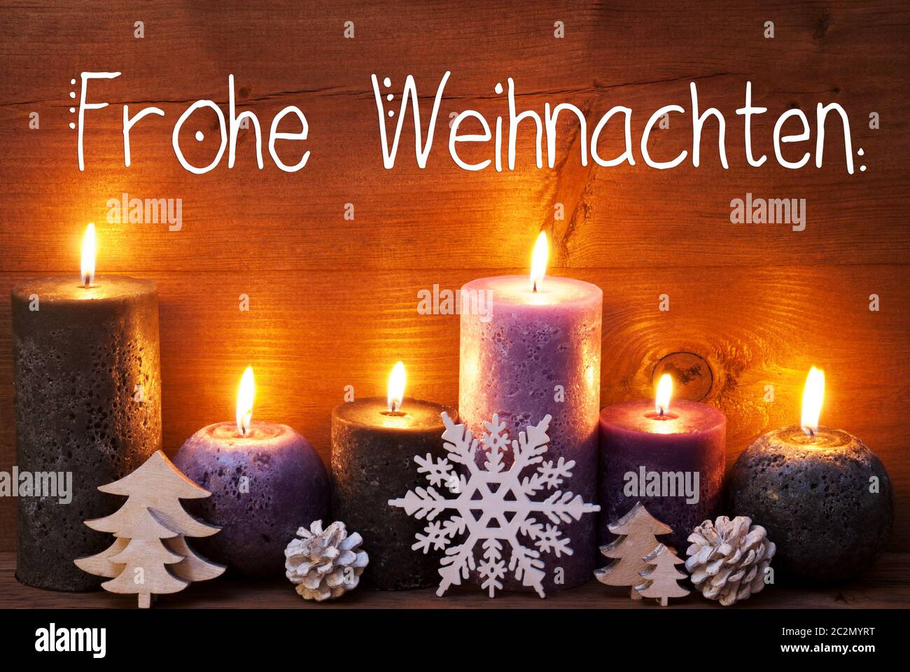 La calligrafia tedesca Frohe Weihnachten significa buon Natale. Viola romantica a lume di candela con ornamento di Natale. Marrone di sfondo di legno Foto Stock