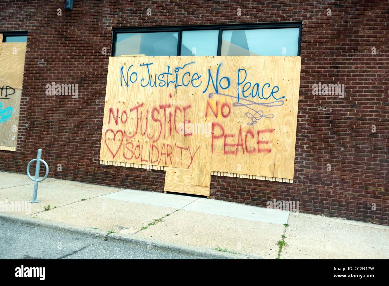 Legno compensato che protegge le finestre del negozio con 'No Justice No Peace Solidarity' scritto con script in grassetto. Minneapolis Minnesota, Minnesota, Stati Uniti Foto Stock
