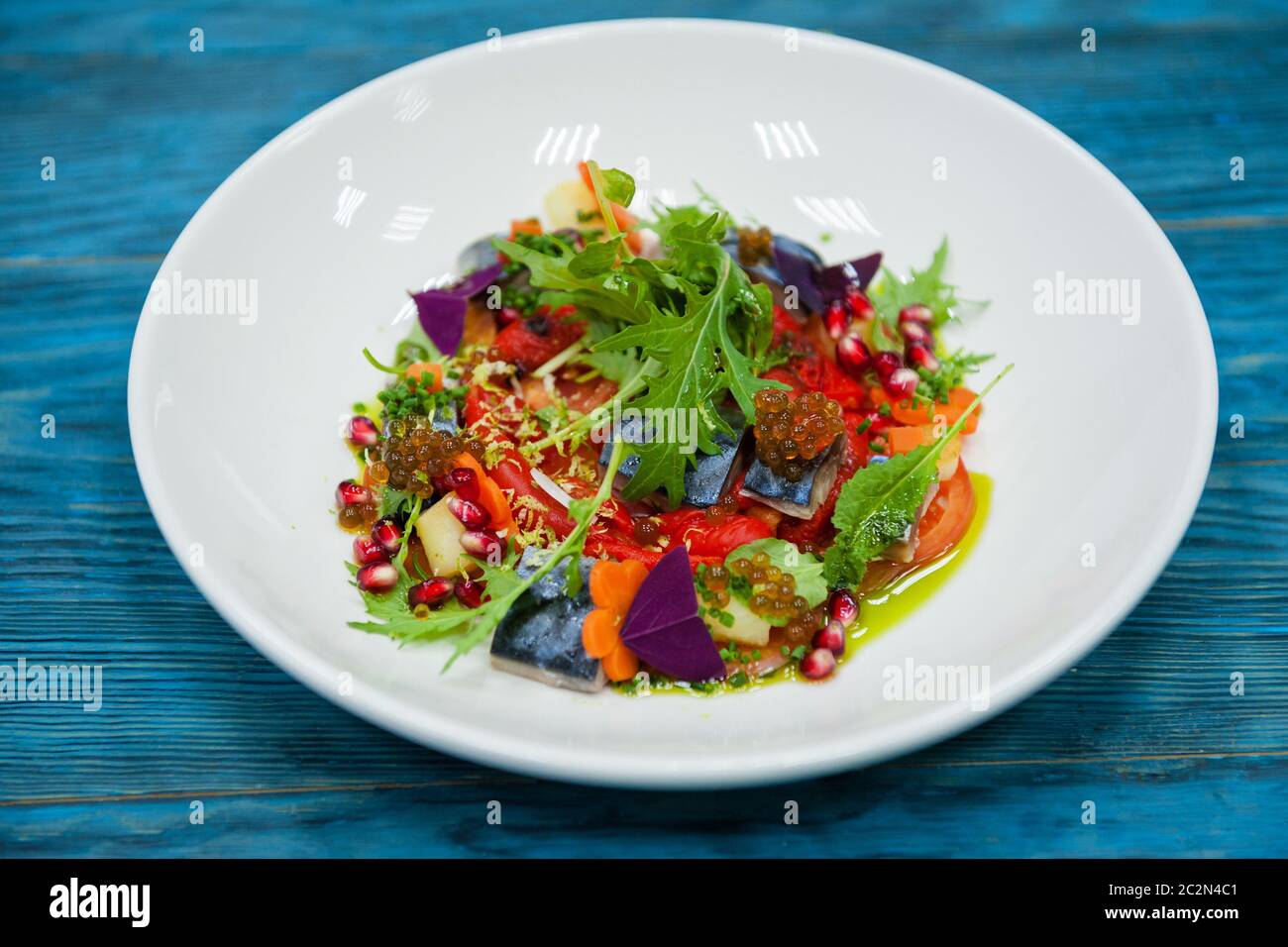 Marinatura piatto di pesce con caviale: sgombro in marinata con verdure, su una piastra sul legno sfondo blu. Foto Stock