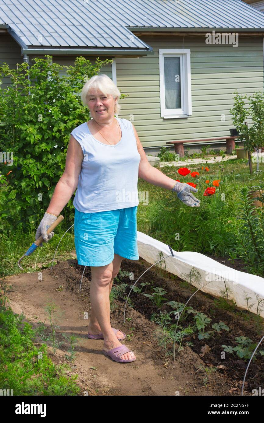 Donna anziana si trova in mezzo al giardino Foto Stock
