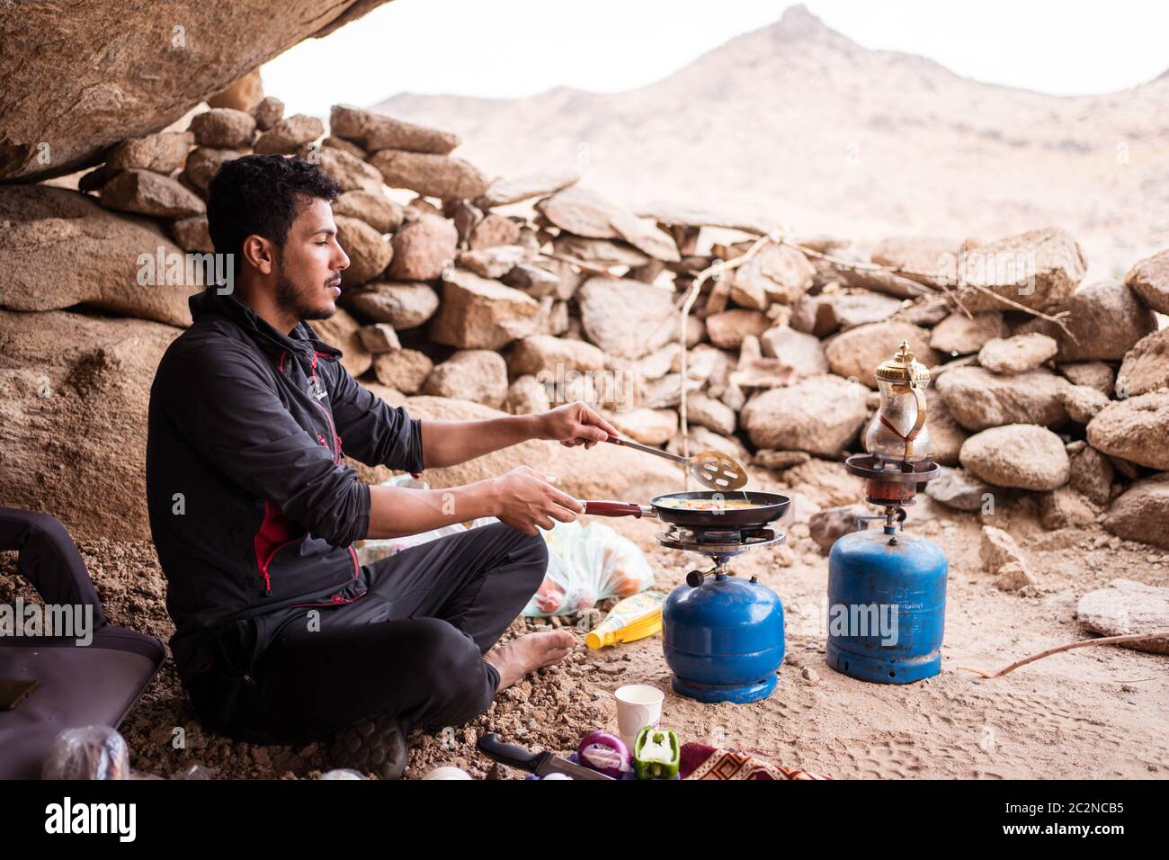 Deserto di Badr / Arabia Saudita - 20 gennaio 2020: Giovane saudita che prepara la colazione nel deserto con stufa a gas in campeggio Foto Stock