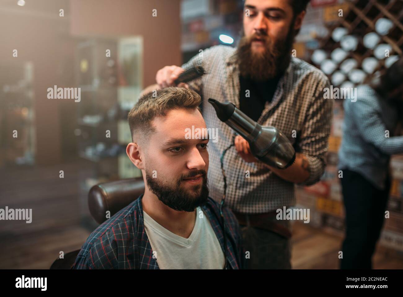 Secco barbiere del cliente i capelli con un asciugacapelli. Parrucchiere interno sullo sfondo Foto Stock